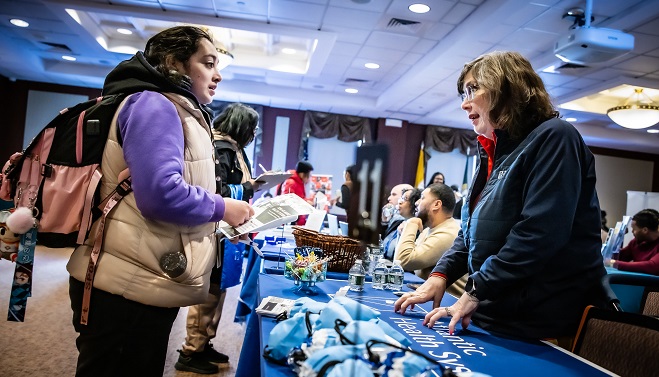 Two professionally dressed individuals talking at a job fair.